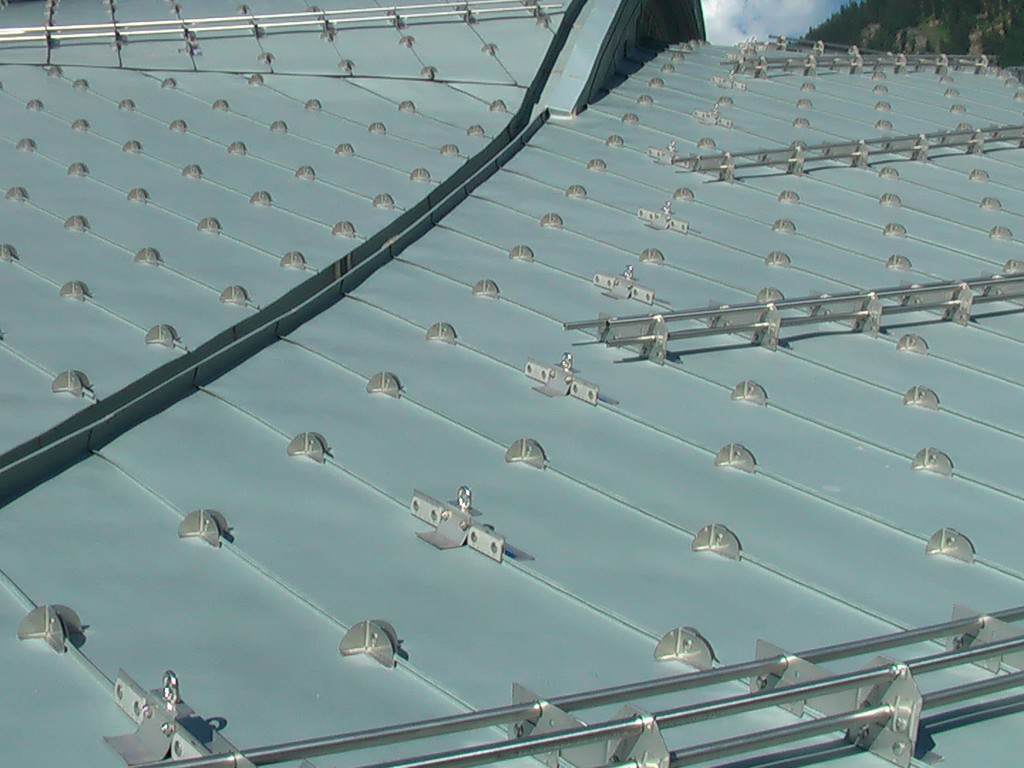 Schneeschutz Dreifachrohrsystem Inox kombiniert mit Schneenasen für Doppelstehfalzdach in Inox inklusiv Entwicklung Produktion Projektierung Zertifizierung und Montage